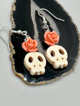 Load image into Gallery viewer, These stylish skull earrings are perfect for adding a unique flair to any outfit. Whether you&#39;re looking for a Dia De Los Muertos accessory or simply looking to draw inspiration, these goth pieces perfectly capture the vampire goth, witchy, dark, Chingona Cabrona, Latina Chicana styles. Crafted with Howlite stone skull beads and peachy coral quartzize floral beaded earrings, this jewelry set is a unique stunning statement piece.  Measurements: 1 1/4 ” in length
