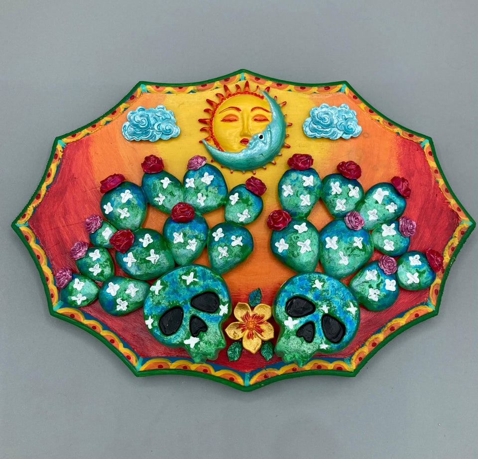 This handcrafted polymer clay wall art features a wood frame painted in a gradient from light yellow to dark red, creating a stunning sunset look. With two bright green skull cactus plant and bright dark red blooming flowers. Featuring a vivid sun and crescent moon with a backdrop of light blue clouds, this frame is sure to make an impression. A bight green hue frame to make a bold contrast with the warm background hue.