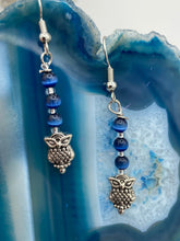 Load image into Gallery viewer, Chic and fun silver-plated owl charm earrings featuring delicate dark blue cats eye beads. Measurements: 1 3/16” in length
