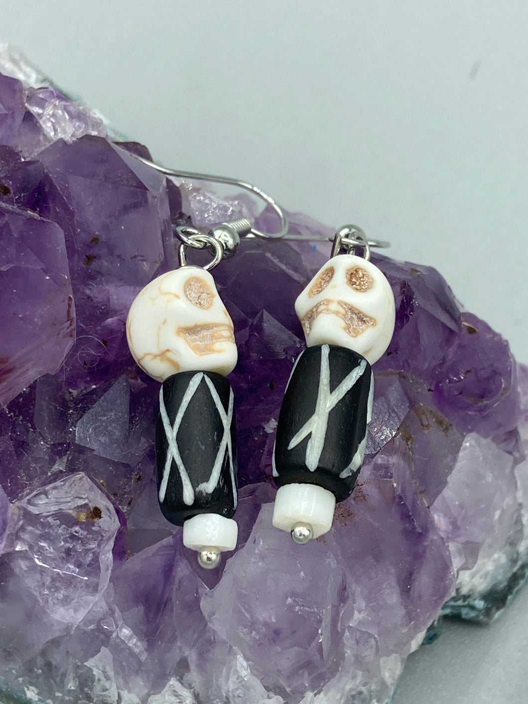 This set of earrings features a mini howlite skull bead with a wood carved black and white bead. Perfect for any goth, emo, witchy, or Day of the Dead outfit, it adds a unique touch to any ensemble.  Measurements: 1 1/2 ” in length 