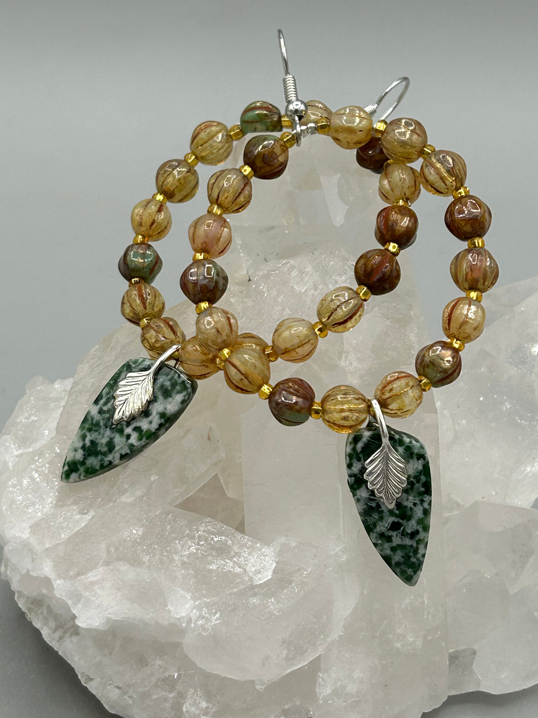 Green-White Qinghai Green Jasper Stone Beaded Hoop Earrings provide a nature-inspired look that is perfect for any boho-chic style. These earrings feature natural green jasper stone triangle pendant with champagne mix melon Czech faceted round glass beads.  Glass beads have a tint of light champagne, amber, dark green and gold shimmer for subtle accent. Show off your bohemian look with these eye-catching hoops. Antique Copper Plated Surgical Steel Hammered Long Ear-wire French Hook Earrings. 