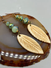 Load image into Gallery viewer, Single-stranded earring features bone carved leaf charm earrings with light mint faceted round glass beads.  Glass beads have a tint of dark green and gold shimmer. Antique Copper Plated Surgical Steel Hammered Long Ear-wire French Hook Earrings.  Measurements: 3” in length  
