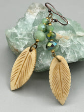 Load image into Gallery viewer, Single-stranded earring features bone carved leaf charm earrings with light mint faceted round glass beads.  Glass beads have a tint of dark green and gold shimmer. Antique Copper Plated Surgical Steel Hammered Long Ear-wire French Hook Earrings.  Measurements: 3” in length  
