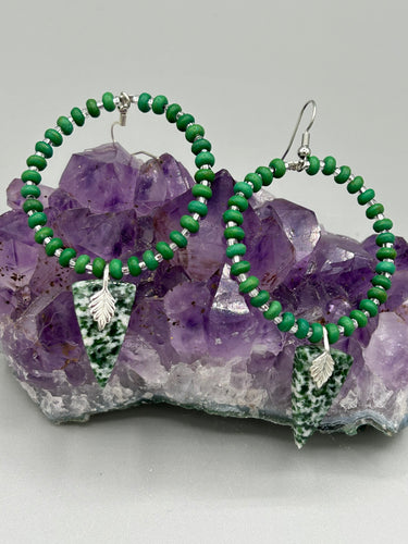 Green-White Qinghai Green Jasper Stone Beaded Hoop Earrings provide a nature-inspired look that is perfect for any boho-chic style. These earrings feature natural green jasper stone triangle pendant with small beads of silver and dark apple green magnesite stone for subtle accent. Show off your bohemian look with these eye-catching hoops.  Measurements: 3