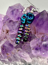 Load image into Gallery viewer, Spooky blue skull beads come with rainbow hematite spine earrings. These stylish skull earrings are perfect for adding a unique flair to any outfit. Whether you&#39;re looking for a Dia De Los Muertos accessory or simply looking to draw inspiration, these goth pieces perfectly capture the vampire goth, witchy, dark, Chingona Cabrona, Latina Chicana styles.   Measurements: 1 1/4” in length
