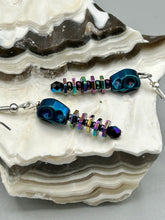 Load image into Gallery viewer, Spooky blue skull beads come with rainbow hematite spine earrings. These stylish skull earrings are perfect for adding a unique flair to any outfit. Whether you&#39;re looking for a Dia De Los Muertos accessory or simply looking to draw inspiration, these goth pieces perfectly capture the vampire goth, witchy, dark, Chingona Cabrona, Latina Chicana styles.   Measurements: 1 1/4” in length
