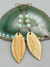Load image into Gallery viewer, Single-stranded earring features bone carved leaf charm earrings with light mint green melon Czech faceted round glass beads.  Glass beads have a tint of light gold shimmer. Antique antique brass plated steel ear-wire French Hook Earrings.   Measurements: 3” in length  
