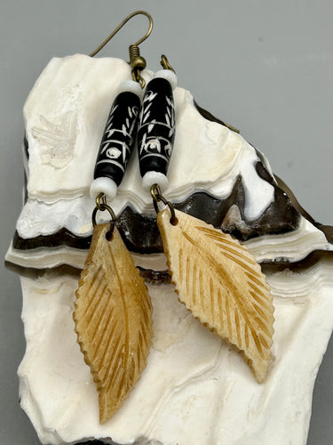 Single-stranded earring features bone carved leaf charm earrings with black and white bone carved floral design beads. Antique brass-plated steel ear-wire French Hook Earrings.   Measurements: 3” in length  