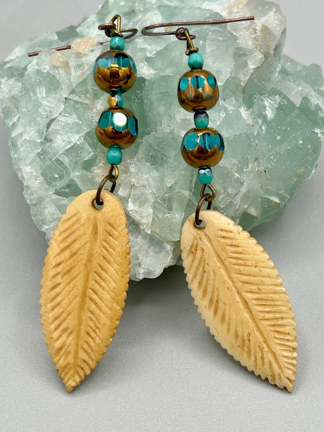 Single-stranded earring features bone carved leaf charm earrings with aqua and copper faceted round glass beads. Antique Copper Plated Surgical Steel Hammered Long Ear-wire French Hook Earrings.   Measurements: 3” in length  