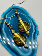 Load image into Gallery viewer, This pair of earrings features a dark amber and green tone, pressed glass leaf charm in an iridescent finish that gives off subtle hues of gold. Complemented with light ming green glass beaded earrings, this set is sure to sparkle.   Measurements: 1 1/4&quot; length

