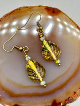 Load image into Gallery viewer, This pair of earrings features a dark amber and green tone, pressed glass leaf charm in an iridescent finish that gives off subtle hues of gold. Complemented with light ming green glass beaded earrings, this set is sure to sparkle.   Measurements: 1 1/4&quot; length
