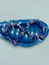 Load image into Gallery viewer, These Lapis Stone Chip Beaded Hoop Earrings feature a dark blue-tone pressed glass leaf charm with an iridescent shimmer finish showcasing hues of gold, purple, blue and pink. The earrings display natural lapis stone chips and royal blue with gold glass beads.  Measurements: 1 1/2&quot; length
