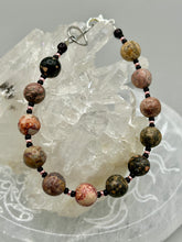 Load image into Gallery viewer, Nature inspired single-strand leopard jasper round stone beads with gold and black glass beaded bracelet. Leopard jasper stone has an array on neutral earth tones including soft pink, salmon, and gray tones. Crafted with metal wire and fastened with a lobster claw clasp.  Measurements:   Bracelet: 7 1/2&quot; in length   
