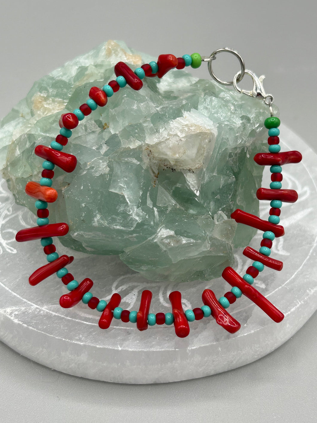 This distinctive Southwestern Style bracelet boasts a captivating combination of large red coral and blue-green turquoise glass beads for a visual impact. Crafted with metal wire and fastened with a lobster claw clasp, this bracelet is sure to command attention.  Measurements:  Bracelet: 8
