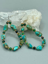 Load image into Gallery viewer, Our Blue-Green Magnesite Stone Beaded Hoop Earrings provide a nature-inspired look that is perfect for any boho-chic style. These earrings feature natural magnesite stone beads with small beads of turquoise and gold glass for subtle accent. Show off your bohemian look with these eye-catching hoops.  Measurements: 2 1/2&quot; length 
