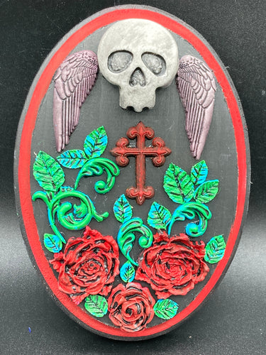 This Memento Mori Wall Art Decor is a one-of-a-kind art piece, skillfully crafted with a black polymer clay skull and wings on a dark red wood frame, decoratively woven with dark red roses and vines. It's perfect for adding an eye-catching touch to any wall and makes a unique, bold gift.  Measurements: H 7