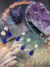 Load image into Gallery viewer, This adjustable collar-style necklace features two shimmery strands of silver and blue glass beads, with three skull charms boasting large, luminous blue teardrop glass beads adding extra shimmer and movement.  Measurements:  Necklace is 14 3/8” adjustable up to 18" in length

