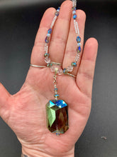 Load image into Gallery viewer, This gorgeous, Bohemian-style necklace features a shimmery aqua blue and gold-toned glass beaded design, with a large, faceted rectangular pendant adding dramatic flair. The vibrant and eye-catching colors make it the perfect way to add a pop of color to any ensemble and the draping style will give you a look that is both bold and elegant.  Measurements:    Necklace is 17” - adjustable to 18&quot;, pendant is 2 1/4”
