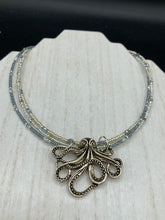 Load image into Gallery viewer, This stylish necklace features a silver plated metal octopus pendant and vibrant iridescent and silver-gray glass beads of various sizes. The Steampunk-inspired design provides a textured, patterned and voluminous look perfect for any dark goth or witchy aesthetic. Measurements:  Necklace measures 15 1/2” adjustable up to 17” in length
