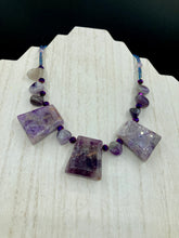 Load image into Gallery viewer, This necklace features large trapezoid-shaped Amethyst pendants and small Amethyst nuggets strung together with shimmery multicolored glass beads, creating a unique and eye-catching statement piece.  Measurements:  Necklace is is 15 1/2” adjustable up to 17&quot;
