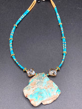 Load image into Gallery viewer, This vibrant and striking double strand necklace features a combination of glass beads in blue and green shades of turquoise, gold and champagne. The two delicate strands are accented with a gold-tone flower-shaped bead, a howlite stone chip dyed in turquoise, and shimmery, cross-faceted champagne-colored glass beads to complete the dramatic look.  Measurements:   Necklace is 17” and can be adjusted up to 19"
