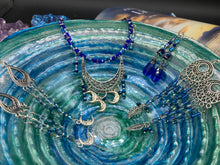 Load image into Gallery viewer, These intricate moroccan blue Inspired large chandelier earrings boast five strands of blue and iridescent glass beads of various hues, including silver and gold. Additionally, two small dark blue glass beads with a silver leaf add a touch of dimension and motion. The perfect addition to any Fairy Princess or whimsical aesthetic.  Measurements: 4” in length
