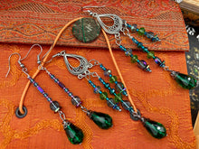 Load image into Gallery viewer, This Whimsical Blue Green Peacock Inspired Beaded Earrings set features bold chandelier style earrings with three long strands of glass bead. These show-stopping pieces boast a range of shimmering shades of blue, green, purple, and gold. A perfect addition to any fashionista&#39;s collection. Measurements: 3 1/2” in length
