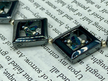 Load image into Gallery viewer, This two-strand necklace, crafted from aqua-blue and silver toned glass beads, is a stunning statement piece. The addition of faceted triangle-shaped glass beads tucked between hematite square beads adds an exquisite and unique flair. The necklace gracefully drapes around the neck, bringing an air of bold and elegant flair to any ensemble it complements. 15” in length, can be extended up to 17"
