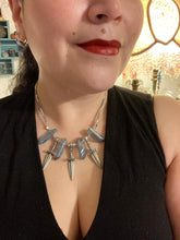 Load image into Gallery viewer, This elegant and dark necklace features shimmering light silver and gray glass beads of varying sizes and shapes for texture and dimension. The necklace is finished with blue luster crystal stone nuggets and nickel-free dagger pendants, creating a beautiful draping effect. Measurements:   Necklace is 17”adjustable up to 19&quot; 
