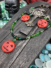 Load image into Gallery viewer, This 25mm bright orange pumpkin bead pendant necklace is a perfect complement to any Halloween ensemble. It is additionally enhanced by shimmery glass beads in classic Halloween hues, such as black, dark green, and light green.  Measurements: Necklace is 19”
