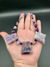 Load image into Gallery viewer, This necklace features large trapezoid-shaped Amethyst pendants and small Amethyst nuggets strung together with shimmery multicolored glass beads, creating a unique and eye-catching statement piece.  Measurements:  Necklace is is 15 1/2” adjustable up to 17&quot;
