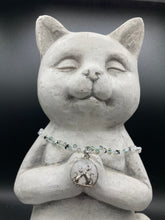 Load image into Gallery viewer, This stylish necklace features a shimmery sterling silver quartz pendant with cats and stars, making it the perfect accessory for any cat lover. With two-hole silver and black beads that stand out against the light aquamarine glass beads, this double strand necklace holds a round kitty pendant made with various hues of clear and iridescent glass beads. Add a touch of purrfection to your look with this statement piece.  Measurements:  Necklace is 15”adjustable up to 18&quot; 
