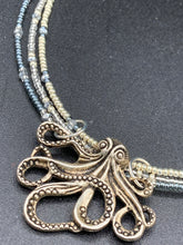 Load image into Gallery viewer, This stylish necklace features a silver plated metal octopus pendant and vibrant iridescent and silver-gray glass beads of various sizes. The Steampunk-inspired design provides a textured, patterned and voluminous look perfect for any dark goth or witchy aesthetic. Measurements:  Necklace measures 15 1/2” adjustable up to 17” in length
