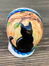 Load image into Gallery viewer, Inspired by nature, ceramic skull is full of vibrant colors and intricate details. The primary color is white with a black cat silhouette and multi-color floral motifs, along with hearts and leaves and lively colorful accents around the entire skull.  Mini skull represented the eternal love for a special kitty cat in your life. Black cat silhouette is sitting on a tree branch admiring the starry night sky. Art created for all the cat lovers who adore their sweet kitty.  Measurements: H 2 3/4” x W 2” x D 2”
