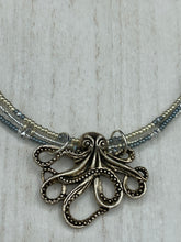 Load image into Gallery viewer, This stylish necklace features a silver plated metal octopus pendant and vibrant iridescent and silver-gray glass beads of various sizes. The Steampunk-inspired design provides a textured, patterned and voluminous look perfect for any dark goth or witchy aesthetic. Measurements:  Necklace measures 15 1/2” adjustable up to 17” in length
