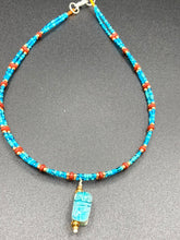 Load image into Gallery viewer, This adjustable choker style necklace features an eye-catching teal wood scarab beetle pendant and glass beaded strands. This dramatic necklace is kept together by double-hole flat matte lava-red beads, providing a collar shape. The necklace artfully wraps around the neck, conveying an elegant and bold style.  Measurements:    Necklace is 14 1/2” in length, can be adjusted up to 16&quot; 
