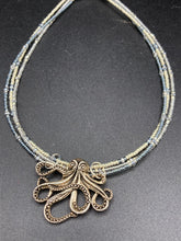 Load image into Gallery viewer, This stylish necklace features a silver plated metal octopus pendant and vibrant iridescent and silver-gray glass beads of various sizes. The Steampunk-inspired design provides a textured, patterned and voluminous look perfect for any dark goth or witchy aesthetic. Measurements:  Necklace measures 15 1/2” adjustable up to 17” in length

