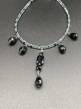 Load image into Gallery viewer, This adjustable collar-style necklace features silver and black glass beads in a combination of both teardrop and rectangular shapes, designed to create visual complexity and depth. The two strands are held together with two-hole silver and black beads, creating a stunningly bold and elegant draped collar that enhances any outfit.
