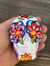 Load image into Gallery viewer, Inspired by nature, ceramic skull is full of vibrant colors and intricate details. The primary color is white with a black cat silhouette and multi-color floral motifs, along with hearts and leaves and lively colorful accents around the entire skull.  Mini skull represented the eternal love for a special kitty cat in your life. Black cat silhouette is sitting on a tree branch admiring the starry night sky. Art created for all the cat lovers who adore their sweet kitty.  Measurements: H 2 3/4” x W 2” x D 2”
