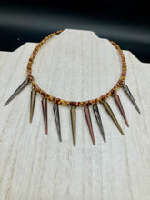 Load image into Gallery viewer, A copper-toned, adjustable Steampunk-style glass beaded necklace is detailed with sharp-drop metal plated hanging beads. Bright orange rectangular tube beads mix with other shapes for an eye-catching effect, while double-hole flat matte copper-toned beads provide a collar finish which makes this piece drape elegantly across the neck. A bold and sophisticated accessory.
