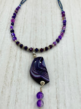 Load image into Gallery viewer, This double-stranded necklace is adorned with a large agate stone displaying a spectrum of purple shades, from light sheer to deep dark tones. The combination of purple agate and multi-colored glass beads makes this pendant a stunning addition to any summer look.  Measurements:  Necklace is 17” in length 
