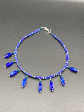 Load image into Gallery viewer, This Vibrant Royal Blue Glass Beaded Choker Necklace features two adjustable strands of deep blue beads with purple hues. The Bohemian style jewelry includes a mixture of rectangular-shaped blue, purple, and silver glass beads, which come together to create an eye-catching and elegant look. Perfect for any outfit, this draping necklace will add a vibrant and bold touch to your style.  Measurements:    Necklace is 14 3/4” in length, can be adjusted up to 16"
