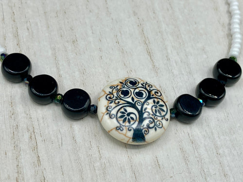 This impressive 24mm reconstituted quartzite lentil bead creates an eye-catching statement piece. The black and white glass beads add a sophisticated touch to its understated tree print. Perfectly suited to casual and formal occasions alike, this stunning necklace will complete any look. It was inspired by the stunning landscapes found in the U.S. National Arboretum in D.C.  Measurements:  Necklace is 17 