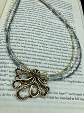 Load image into Gallery viewer, This stylish necklace features a silver plated metal octopus pendant and vibrant iridescent and silver-gray glass beads of various sizes. The Steampunk-inspired design provides a textured, patterned and voluminous look perfect for any dark goth or witchy aesthetic. Measurements:  Necklace measures 15 1/2” adjustable up to 17” in length
