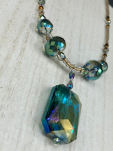 Load image into Gallery viewer, Make a bold statement with this shimmery aqua blue and gold tones glass beaded necklace. The large rectangular faceted shaped pendant creates a vivid contrast to the warm gold tones of the necklace, perfect for adding a rich pop of color to any Spring outfit. The draped design gives this piece an elegant, bohemian look. Measurements:    Necklace is 20” in length, 
