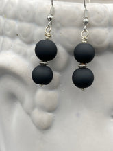 Load image into Gallery viewer, These flat matte black glass bead earrings are perfect for creating a cocktail chic ensemble. With a round shape and silver plated floral bead, this timeless piece is ideal for special occasions such as weddings. Its minimalist look exudes effortless elegance. Measurements: 1 1/4” in length
