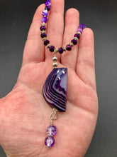 Load image into Gallery viewer, This double-stranded necklace is adorned with a large agate stone displaying a spectrum of purple shades, from light sheer to deep dark tones. The combination of purple agate and multi-colored glass beads makes this pendant a stunning addition to any summer look.  Measurements:  Necklace is 17” in length 
