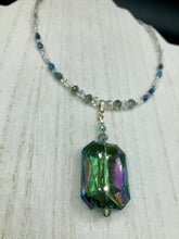 Load image into Gallery viewer, This gorgeous, Bohemian-style necklace features a shimmery aqua blue and gold-toned glass beaded design, with a large, faceted rectangular pendant adding dramatic flair. The vibrant and eye-catching colors make it the perfect way to add a pop of color to any ensemble and the draping style will give you a look that is both bold and elegant.  Measurements:    Necklace is 17” - adjustable to 18&quot;, pendant is 2 1/4”

