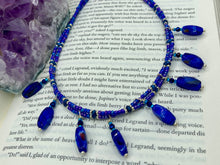 Load image into Gallery viewer, This Vibrant Royal Blue Glass Beaded Choker Necklace features two adjustable strands of deep blue beads with purple hues. The Bohemian style jewelry includes a mixture of rectangular-shaped blue, purple, and silver glass beads, which come together to create an eye-catching and elegant look. Perfect for any outfit, this draping necklace will add a vibrant and bold touch to your style.  Measurements:    Necklace is 14 3/4” in length, can be adjusted up to 16"
