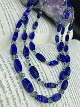 Load image into Gallery viewer, This vibrant royal blue and silver-tone necklace is adjustable and features an eye-catching three-strand design. The rectangular blue glass beads are predominant, complemented by a blend of lighter blue and silver beads for an intriguing multi-hued finish. By mixing shapes and tones, it creates a complex, dimensional look. The draped effect adds a fierce yet elegant pizzazz to any outfit. Perfect for the season of Spring, it will bring a splash of rich color to your wardrobe. 
